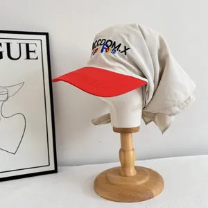 Detail of red and beige sun hat with neck flap and colorful REEDOM.X embroidery