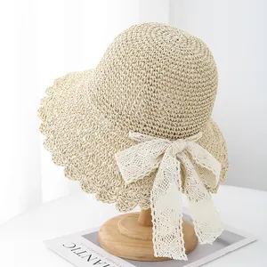 Close-up of fine hand-woven straw hat with delicate scalloped edges and white lace bow