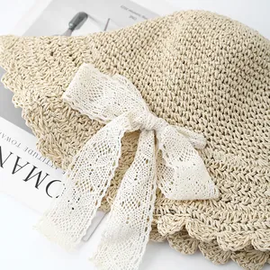 Detailed close-up of a beige woven straw hat with elegant white lace bow and wavy brim