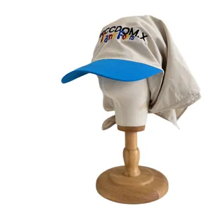 Beige baseball cap with blue brim featuring Freedom.X embroidery and long neck protection cover