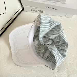 Detailed interior of 100% cotton striped baseball cap with metal buckle and care label