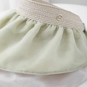 Detail of straw sun hat with light green chiffon fabric and a gold fashion buckle