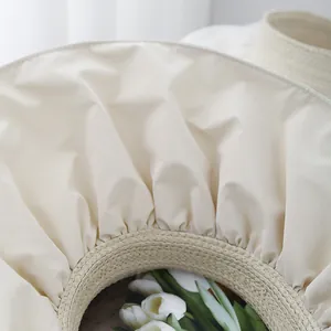 Detailed view of sun hat showing straw texture and off-white pleated waterproof fabric