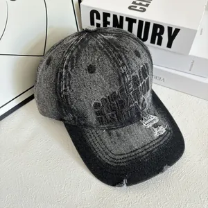 Détail de la casquette en denim délavé avec broderie vintage et bordure déchirée