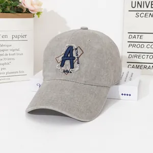 Grey washed cotton baseball cap with blue letter A embroidery on a minimalist background