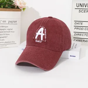 Detail of vintage burgundy baseball cap with white letter embroidery on a clean background