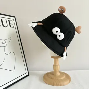 Detail of black cotton bucket hat featuring funny cartoon eyes and glove decorations