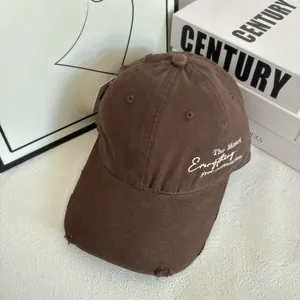 Detail of distressed brown baseball cap featuring side embroidery and vintage torn texture