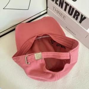 Detail of pink cotton baseball cap featuring metal buckle adjustment and inner embroidery