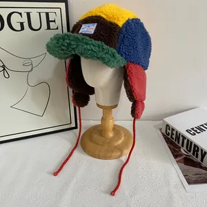 Detalle de gorro de aviador de lana de cordero patchwork con orejeras y cordones rojos