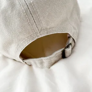 Detalle de hebilla de metal bronce en gorra de béisbol de algodón sarga color beige