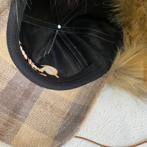 Detail view of plaid earflap hat with faux fur lining and soft fabric inner texture