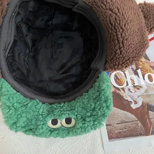 Detalle del gorro de lana de cordero con ojos de dibujos animados y visera verde suave