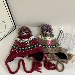 Winter jacquard knit earflap hat with pompom and tassels in burgundy and brown colors