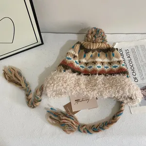 Détail du bonnet en tricot ethnique avec doublure en peluche et tresses à pompons