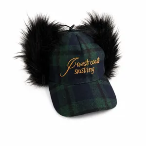 Fuzzy plaid baseball cap with black faux fur pom-poms and West Coast embroidery