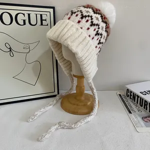 Detail of Fair Isle knit trapper hat with pom-poms and warm ear flaps in cream white