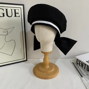 Sweet sailor style black beret with white stripes and large bow on model head display