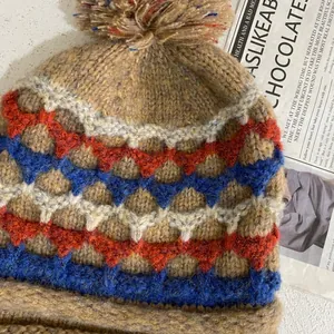 Detailed knit texture of a brown Fair Isle winter beanie with a fluffy pom-pom top