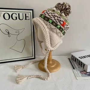 Close-up of geometric jacquard knit pattern and colorful pom-poms on the winter earflap hat