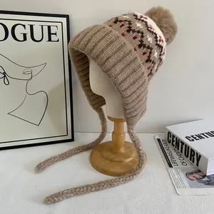 Detailed knit pattern of Fair Isle winter earflap hat with fluffy pom-poms and braids