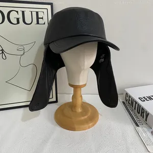 Vintage black faux leather trapper hat with earflaps and snap buttons on a wooden stand