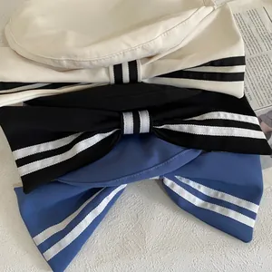 Close-up of sailor-style berets showing striped ribbons and large bow details in three colors