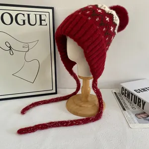 Detailed knit of red Fair Isle earflap hat with pompom and plush lining for winter