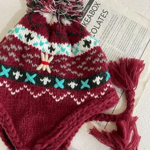 Detailed knit texture of dark red earflap hat with colorful jacquard patterns and pom-pom
