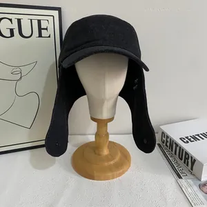 Vintage black aviator hat with long ear flaps and textured fabric on white background