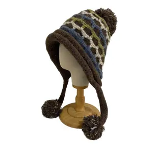 Fair Isle knit winter hat with ear flaps and pom-poms on a wooden display stand