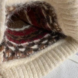 Macro detail of Fair Isle knit pattern and beige fleece lining on a winter trapper hat