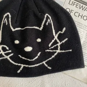 Gros plan sur la maille côtelée et le motif jacquard de chat blanc sur le bonnet noir