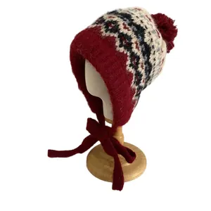 Winter Fair Isle knit earflap hat with pompom and Nordic pattern on a wooden stand