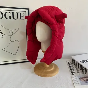 Détail de la chapka rouge matelassée avec cornes de diable sur un support en bois
