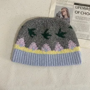 Detalle del gorro de punto jacquard con motivos de golondrinas y bordado floral