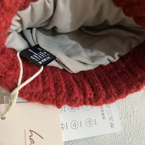 Detalle del gorro de punto rojo con forro suave y etiqueta de cuidado de calidad