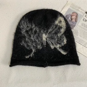 Close-up of a black knit beanie with butterfly pattern and soft mohair texture