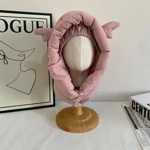 Détail de la capuche rembourrée rose clair avec ailes décoratives et bouton pression