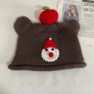 Detailaufnahme der handgestrickten Bärenohrenmütze mit Weihnachtsmann-Applikation