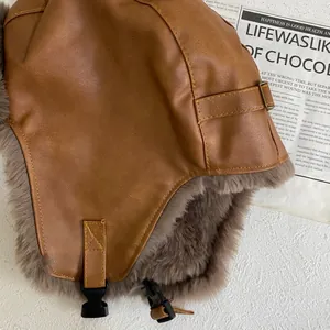 Close-up of brown PU leather texture and thick faux fur lining on a winter aviator hat
