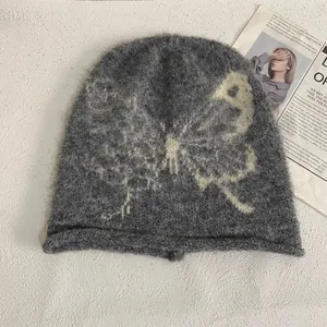 Detail of dark grey mohair beanie featuring a cream butterfly jacquard and fuzzy texture