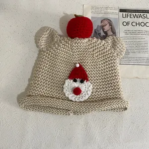Detailansicht der handgestrickten beige Bärenmütze mit 3D-Apfel und Weihnachtsmann-Aufnäher