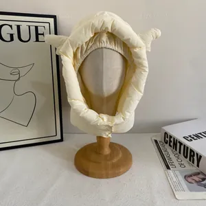 Détail du bonnet d'hiver matelassé crème avec cornes décoratives et bouton au cou