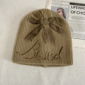 Khaki rib-knit beanie featuring bow detail and Illegal graffiti print for women