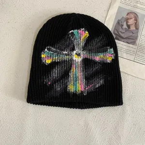 Black ribbed knit beanie with colorful graffiti cross print on a textured background