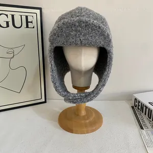 Dettaglio del cappello da aviatore grigio in peluche su manichino con sfondo di moda