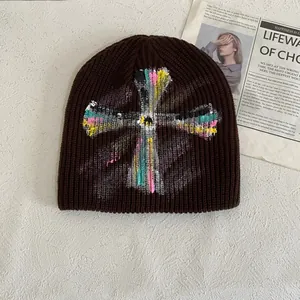 Detail of dark brown knitted beanie featuring colorful graffiti-style cross embroidery