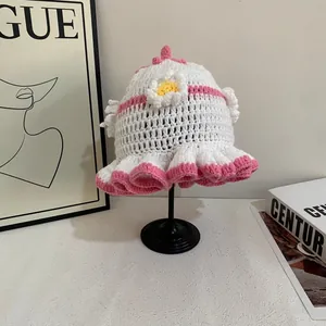 Detail of white crochet knit hat with pink wavy brim and 3D daisy flower decoration