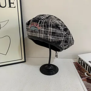 Detail view of the vintage plaid beret featuring embroidery and black leather trim